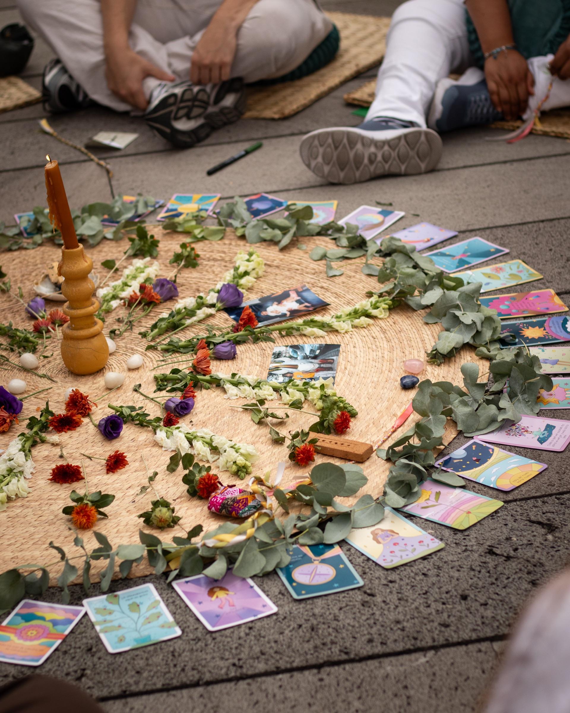 El mandala terminado: flores, eucalipto y cartas ilustradas en círculo sobre el petate