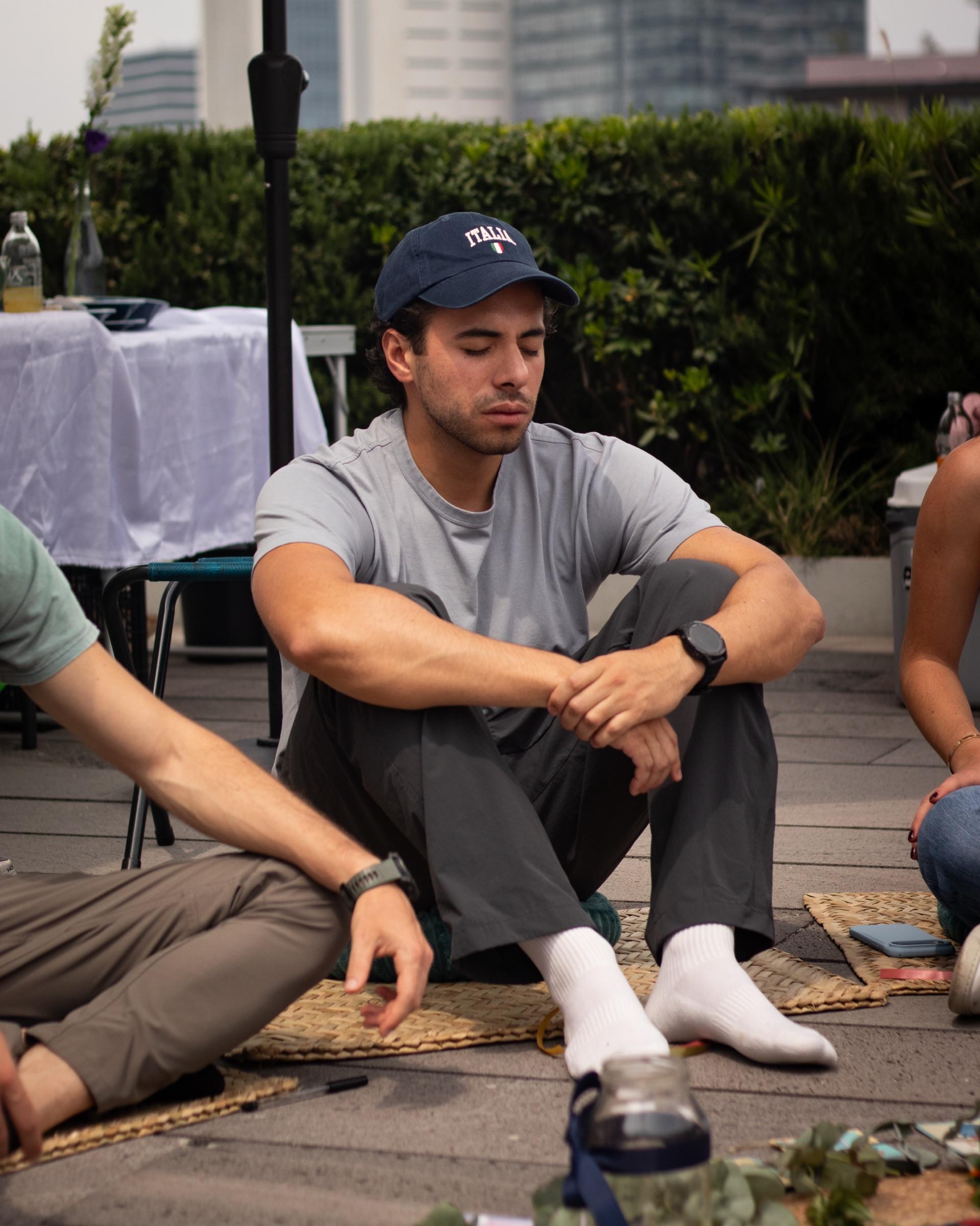 Un participante sentado en el petate, con los ojos cerrados, durante la meditación