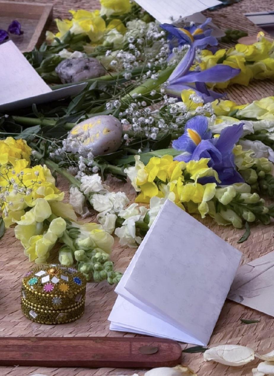 Mesa de ofrenda con flores, cuaderno y objetos rituales